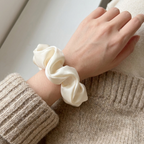 Scrunchie i hvit på en arm. 